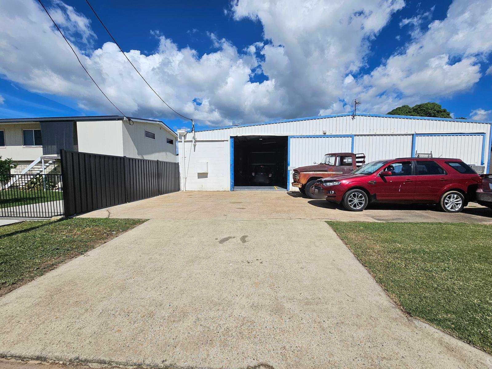 The Townsville Car Care shed on Oonoonba Road, white cladding with blue trim and cars parked out front